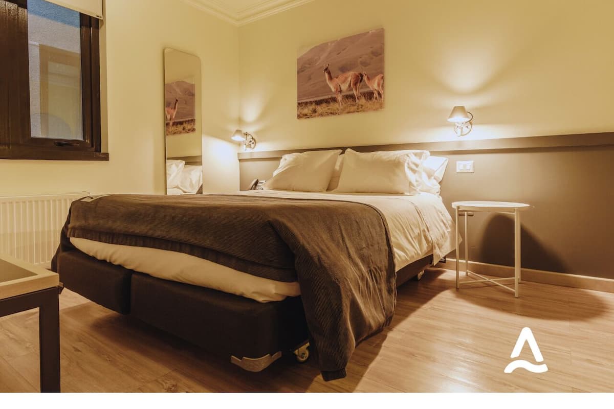 A bedroom with a bed, bedside table, and wall art.