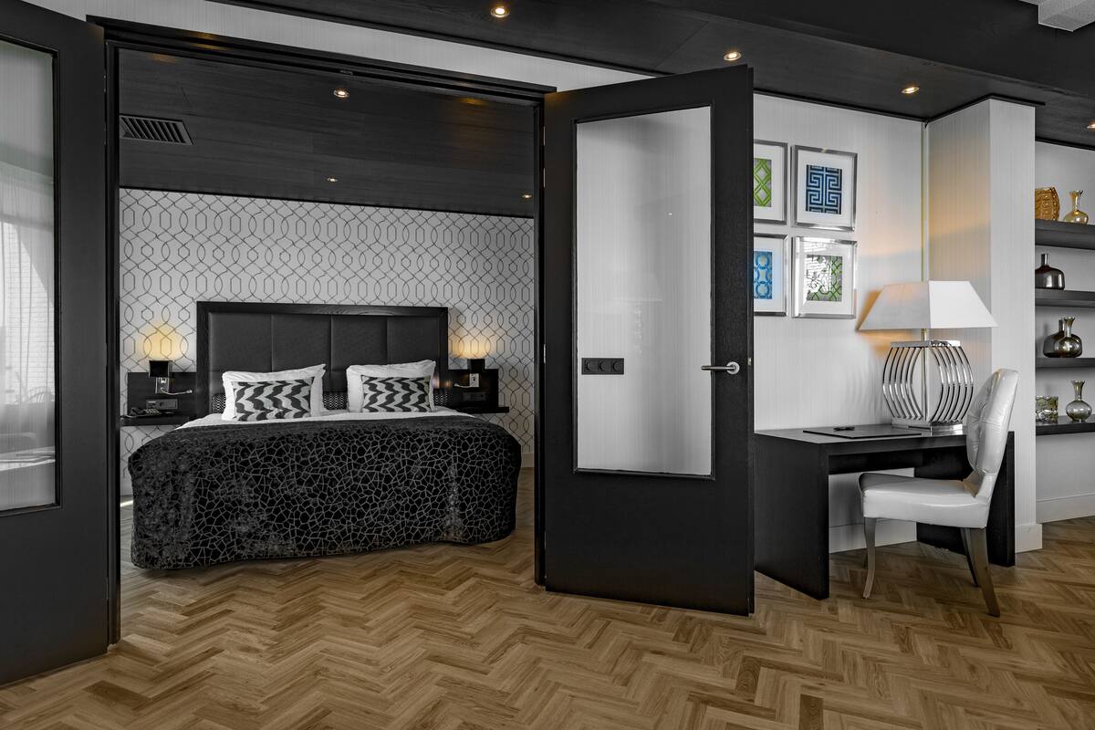 A modern bedroom with a bed, bedside tables, a desk, and a chair.