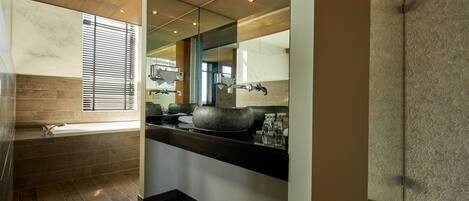 Un baño moderno con una bañera grande, un lavabo de piedra y un espejo sobre el lavamanos.