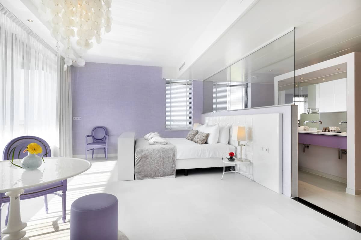 A modern bedroom with a bed, bedside table, and a large mirror.