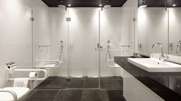 A modern bathroom with a glass shower enclosure, a white toilet, and a black countertop with a sink.
