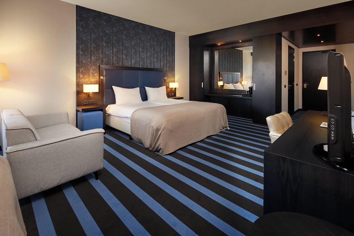 A hotel room with a large bed, a desk, a chair, and a television.