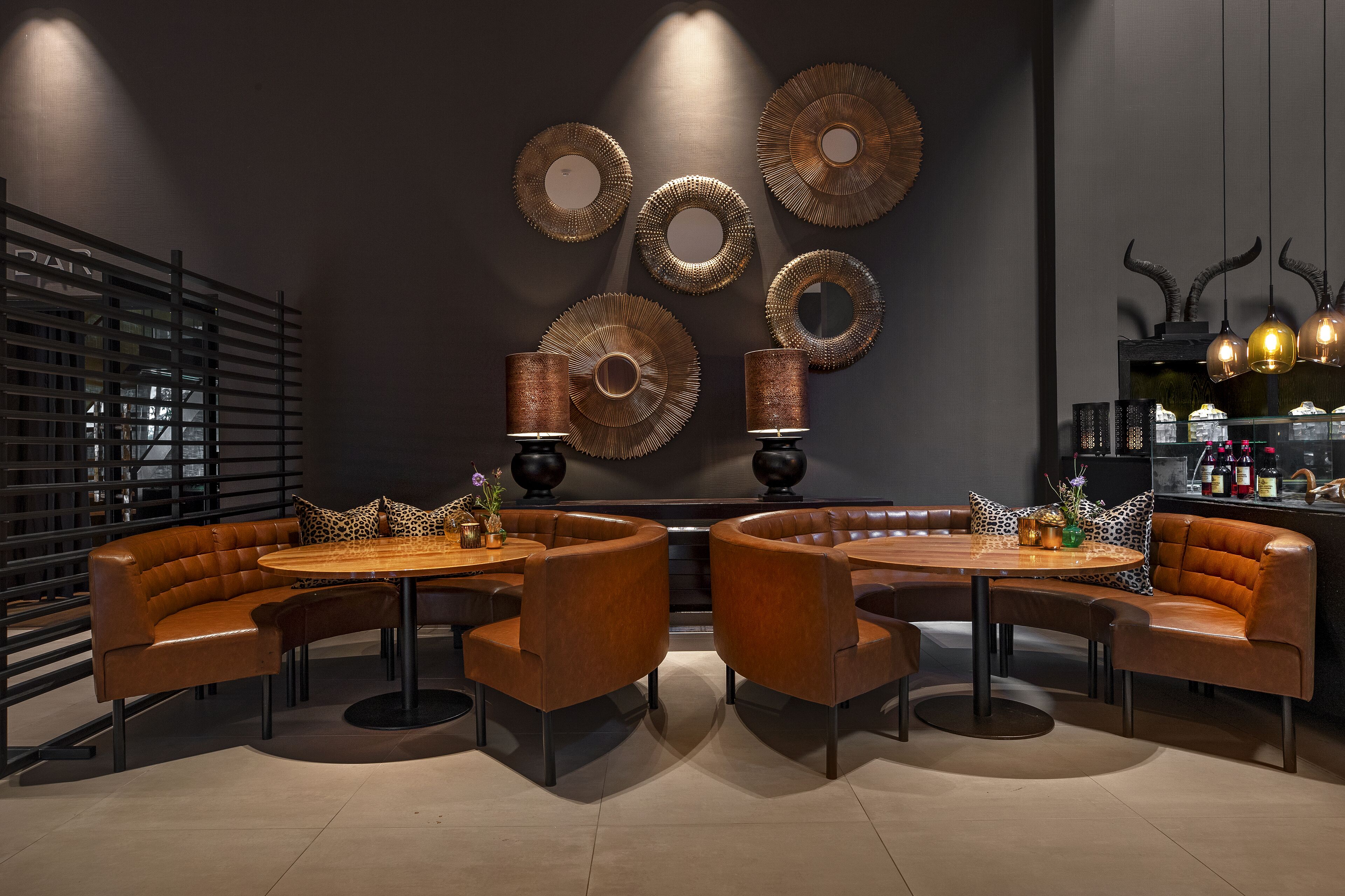 Un espace détente moderne avec des canapés en cuir, une table ronde et des œuvres d’art décoratives murales.