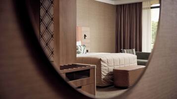 A modern hotel room with a bed, bedside table, and a small seating area.