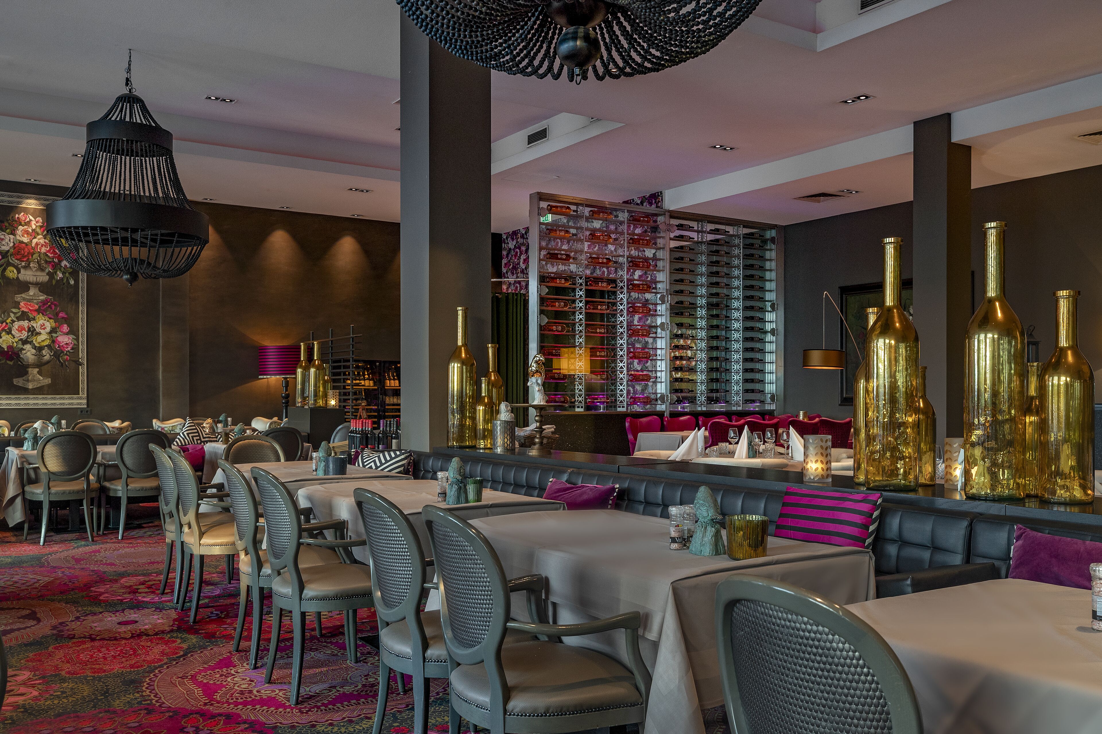 A restaurant with round tables, cushioned booths, and a patterned carpet.