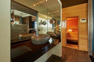 Casa de banho moderna com um espelho grande, duas pias de granito e uma sauna.