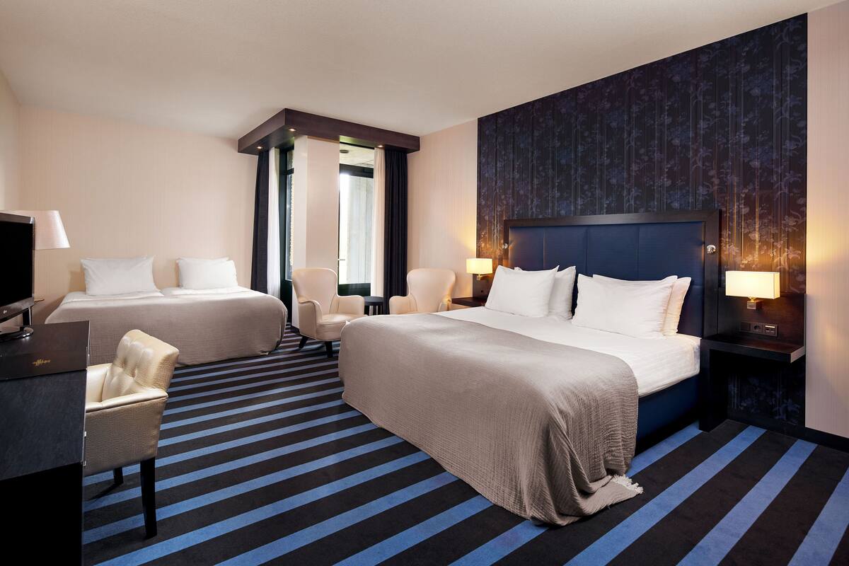 A hotel room with two beds, a desk, and a chair.