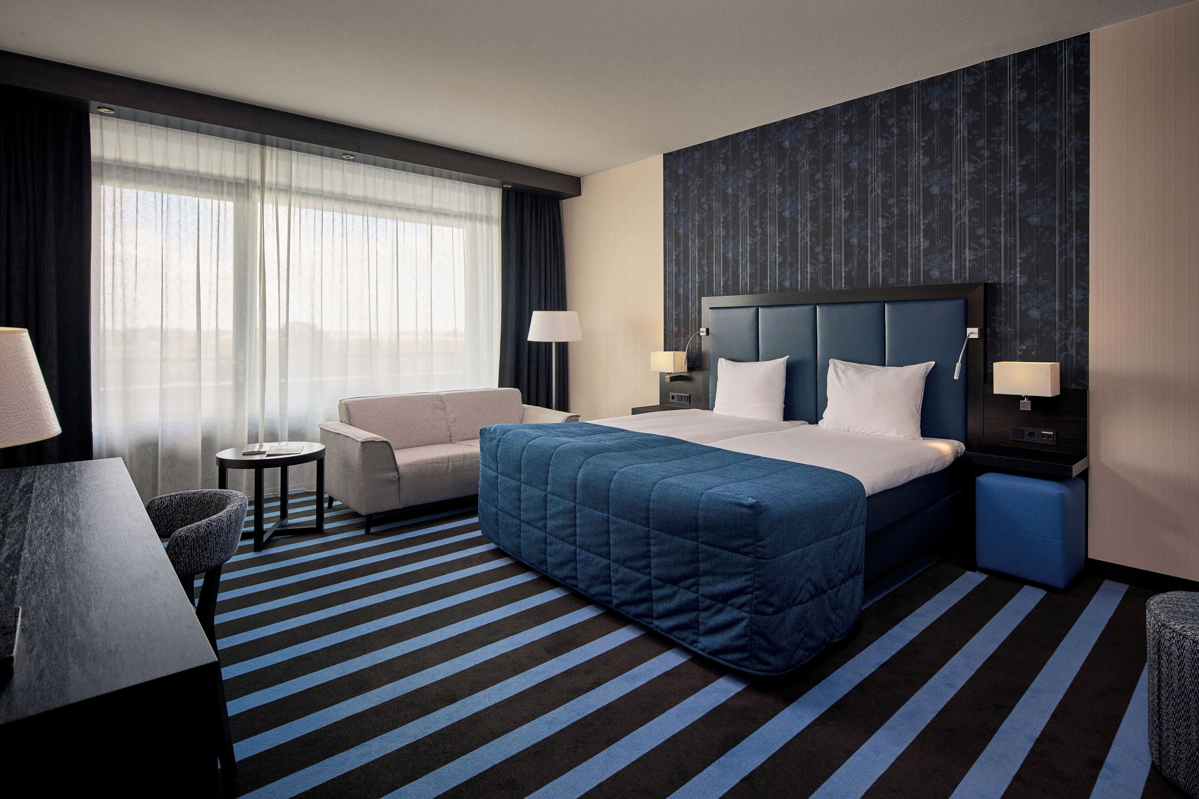 Une chambre d’hôtel avec un grand lit, un canapé, un bureau et une chaise.