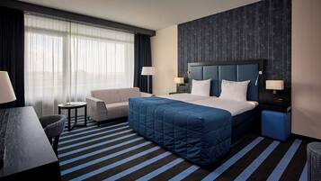 Une chambre d’hôtel avec un grand lit, un canapé, un bureau et une chaise.