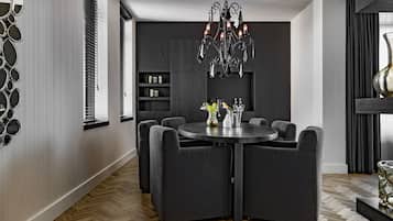 Un comedor moderno con una mesa redonda, sillas oscuras y una araña.