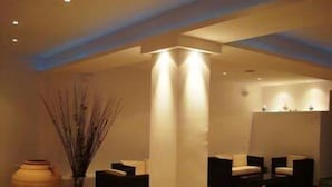 A modern interior with a reception desk, seating area, and a large vase with branches.