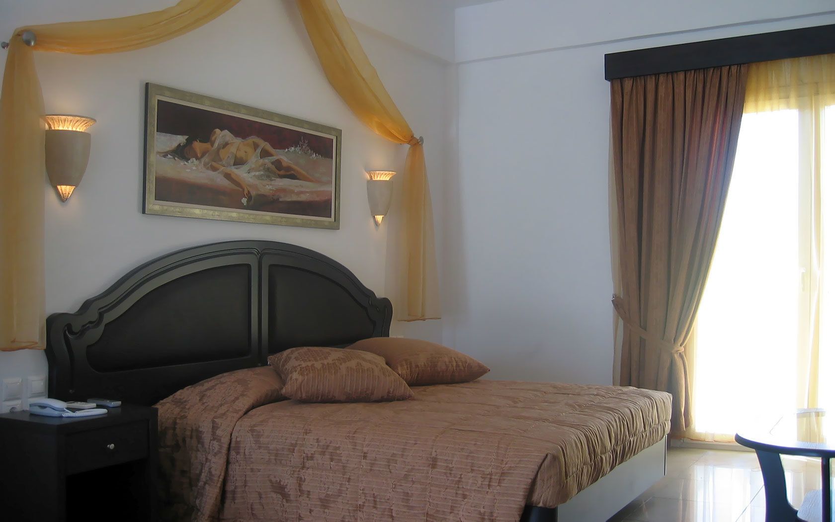 A hotel room with a large bed, two bedside lamps, a painting on the wall, and a window with curtains.