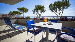 A terrace with a table and chairs, overlooking a body of water and trees. - Hotel More (Split)