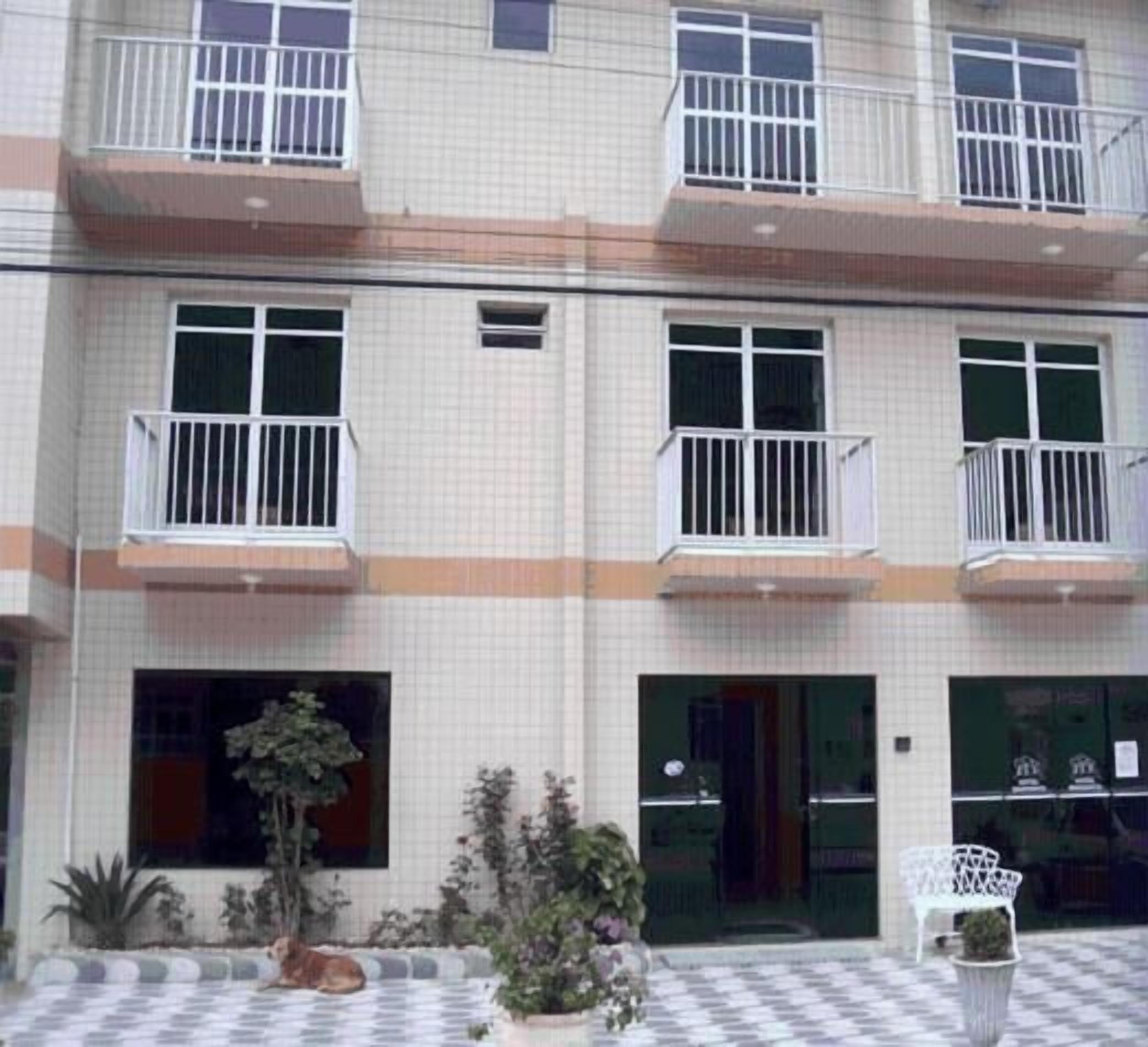 A multi-story building with balconies, a tiled facade, and a checkered floor pattern.