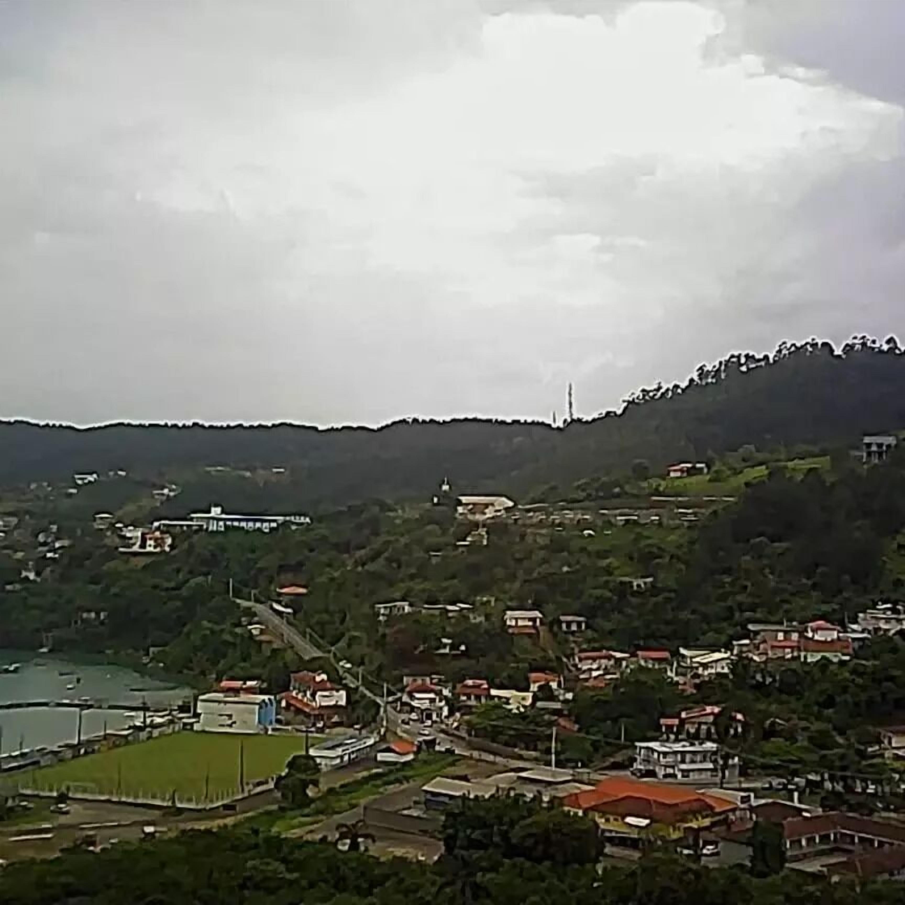 Un pueblo costero con edificios, una iglesia y una colina al fondo.