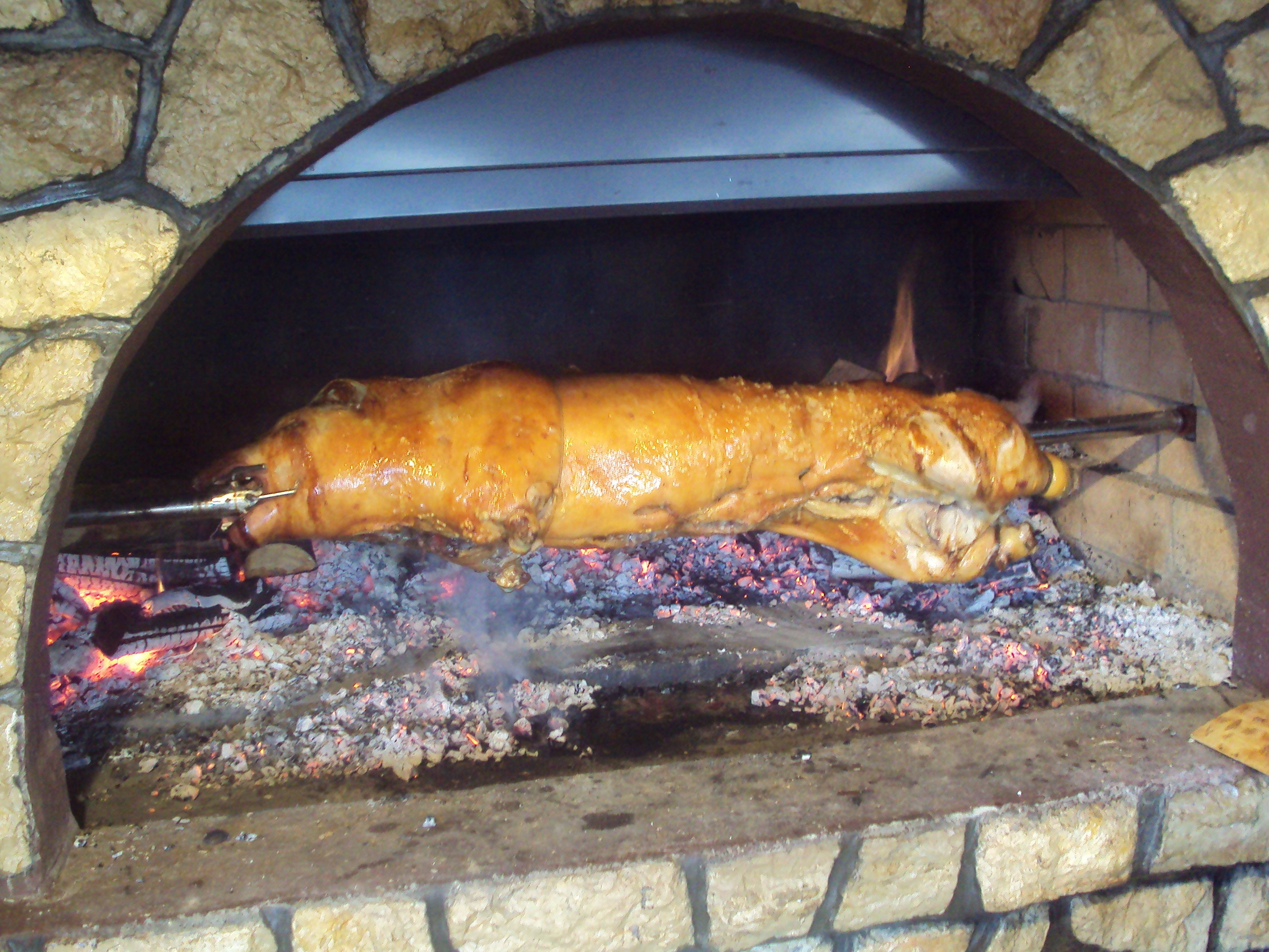A large roasted pig in a stone oven.