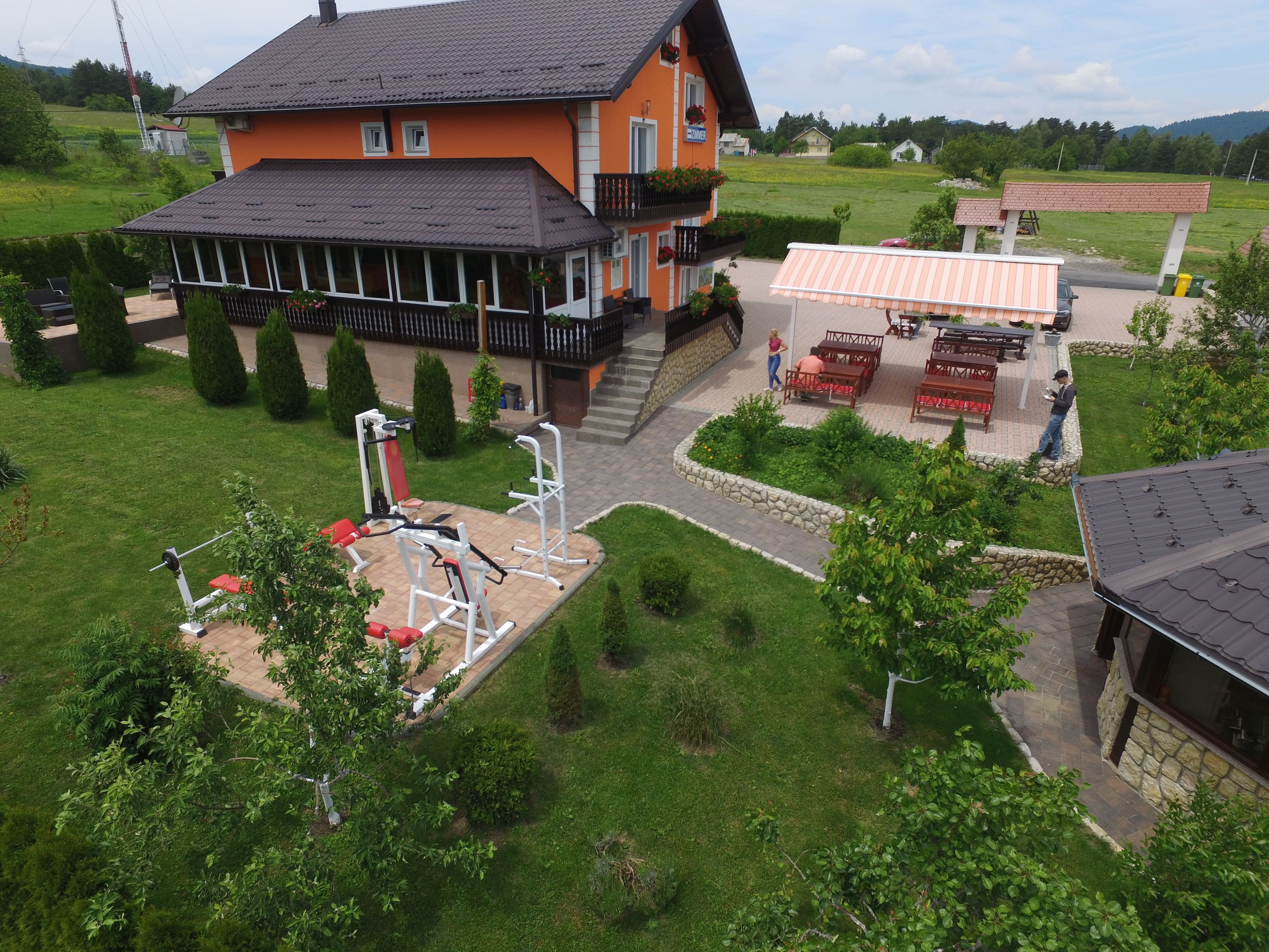 A house with a balcony, outdoor exercise equipment, and a patio area with tables and chairs.