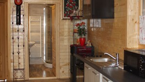 A wooden interior with a kitchen area featuring a sink, cabinets, and a microwave. - Pension Perisic (Plitvicka Jezera)