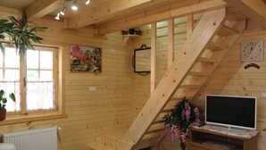 A wooden interior with a staircase, a radiator, a television on a wooden stand, and a painting on the wall. - Pension Perisic (Plitvicka Jezera)