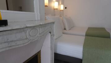 A room with a bed, a bedside table, a mirror, and wall-mounted lights.