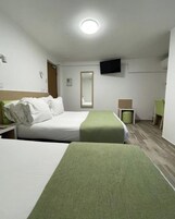 A hotel room with two beds, a flat-screen TV mounted on the wall, a small table, and a chair.