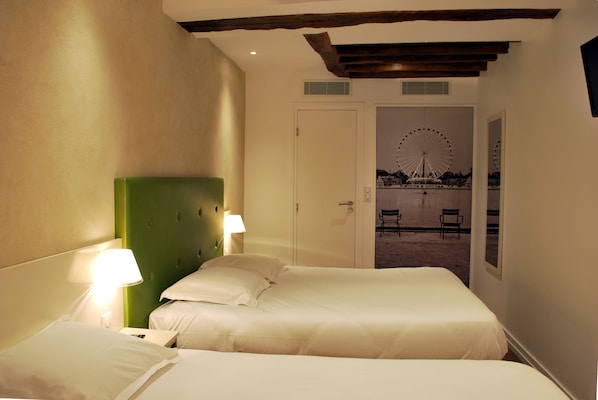Habitación de hotel con dos camas, cabecera verde y vista a una noria a través de una puerta abierta.