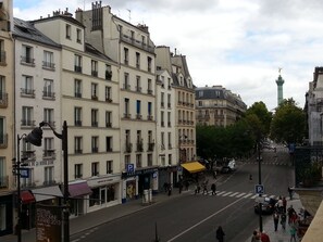 Vista de una calle en París con edificios históricos, un paso de peatones y personas caminando.