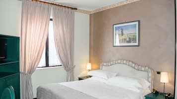 Quarto de hotel com cama, duas luminárias de cabeceira, televisão e janela com cortinas.