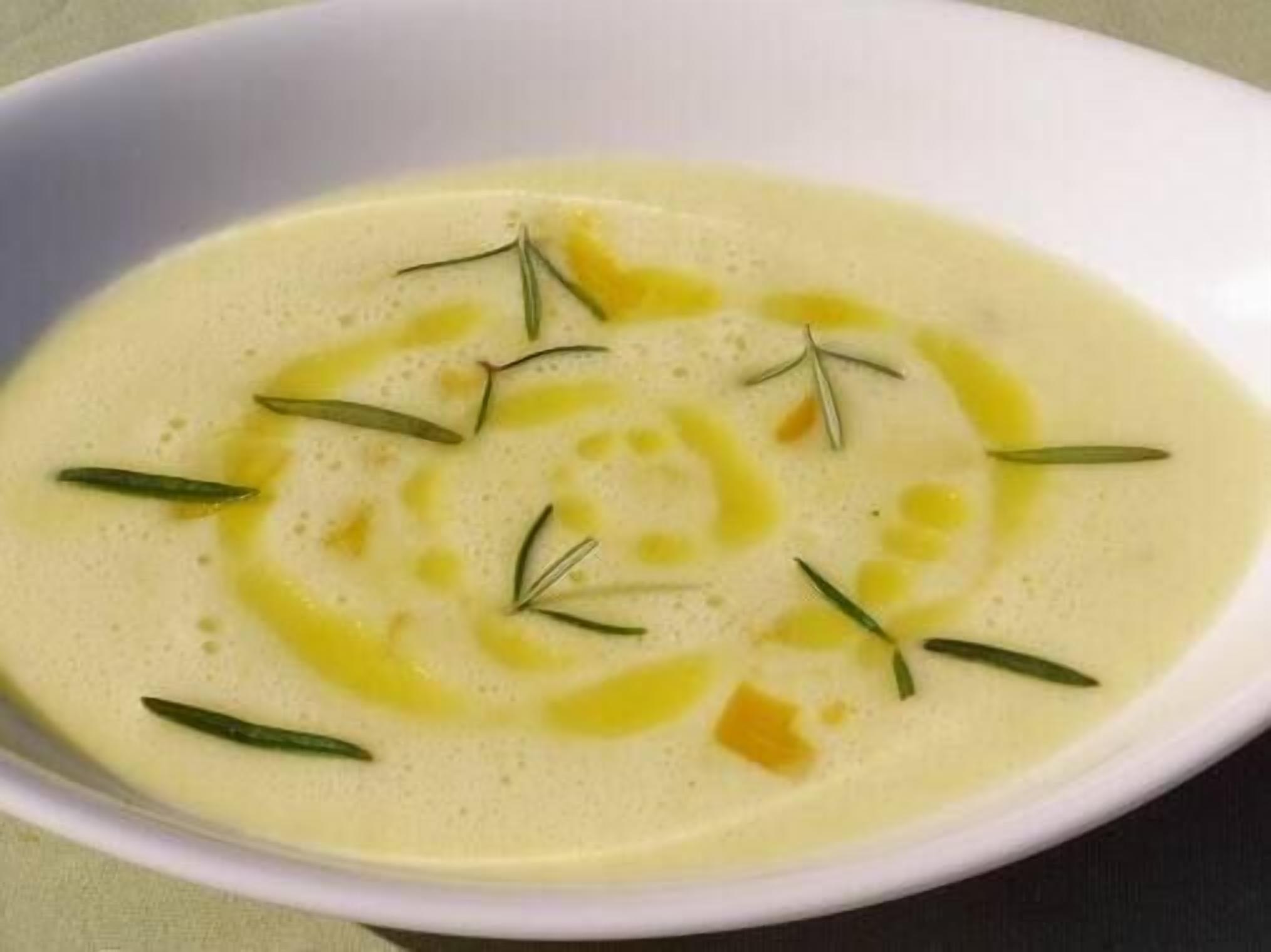 Un tazón de sopa cremosa adornada con hierbas.