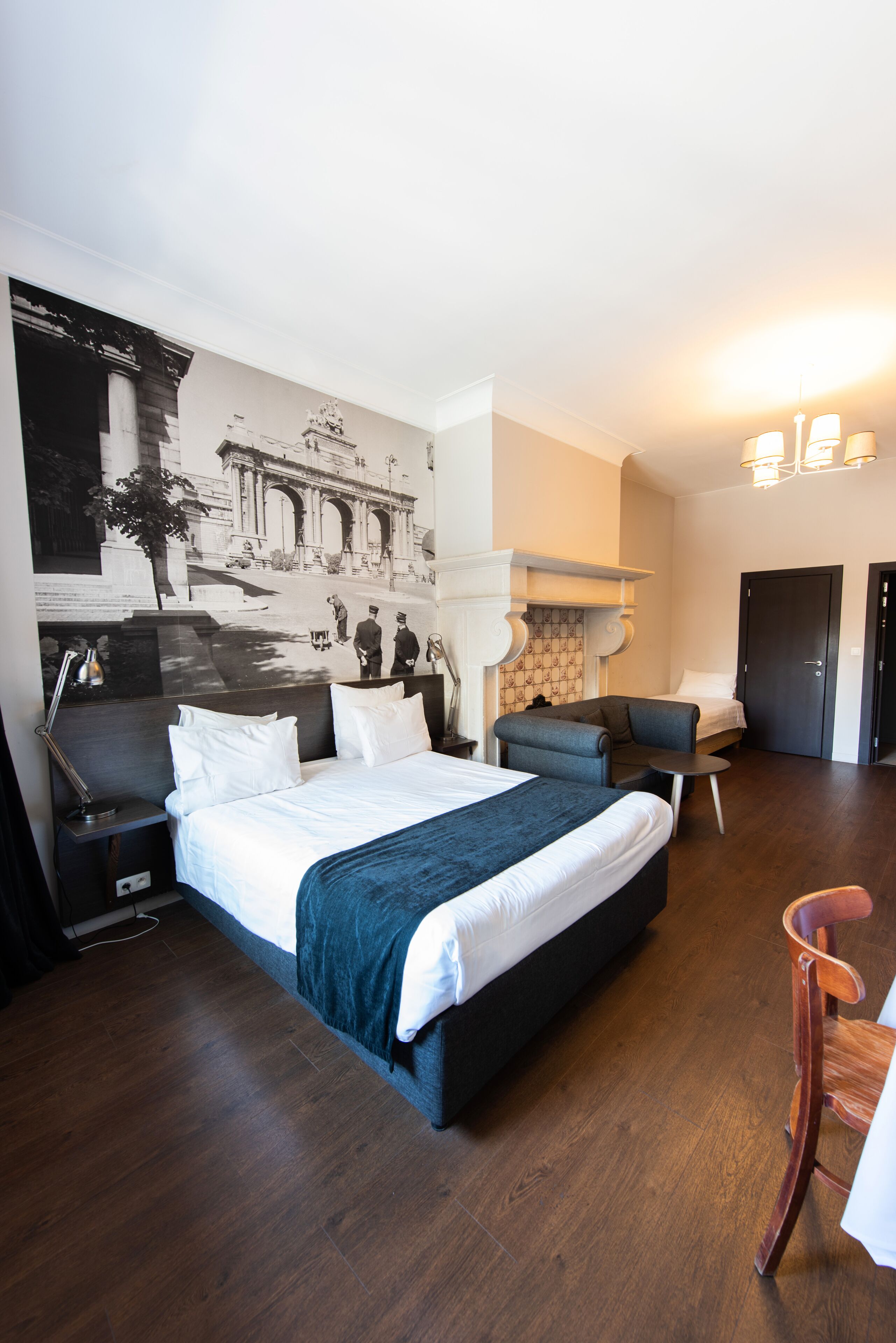 Une chambre d’hôtel avec un grand lit, un bureau, une chaise, une petite table et une fresque murale.