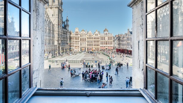 Vista desde una ventana con vista a una plaza histórica y un edificio grande al fondo.
