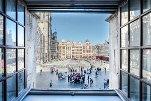 A view from a window overlooking a historic square with a large building in the background.