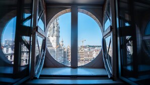 Una ventana redonda con vista a un edificio histórico y grúas de construcción.