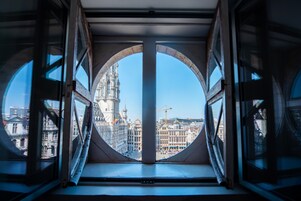 A circular window with a view of a historic building and construction cranes.