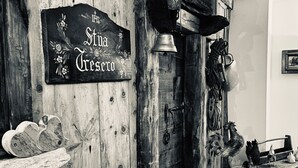 A rustic interior with a wooden wall, a bell, a rooster sculpture, and a heart-shaped decoration. - Genzianella (Valfurva)
