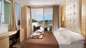A hotel room with a bed, a desk, a chair, and a view of the outdoors. - Hotel Sarti (Riccione)
