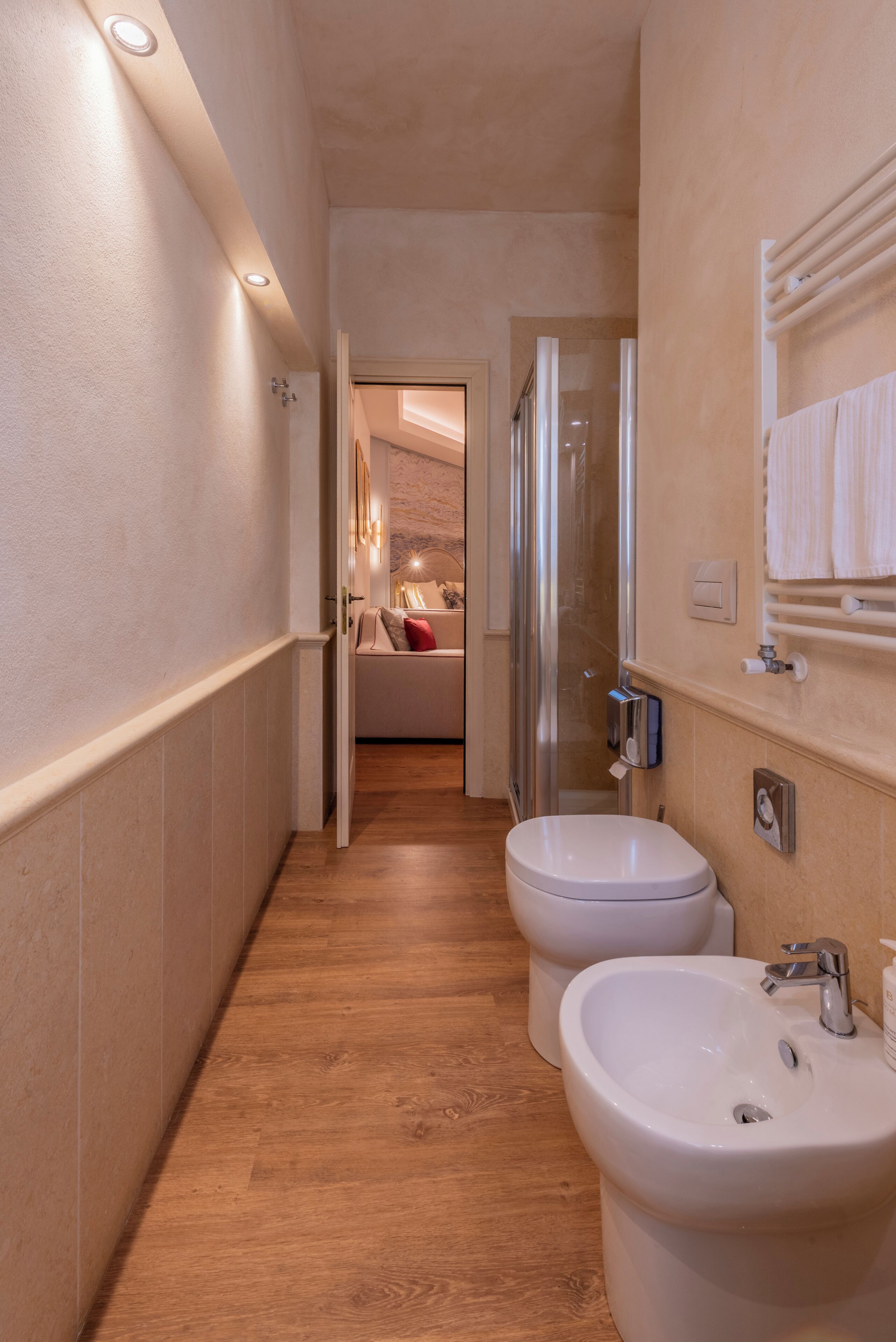 A narrow hallway leading to a bathroom with a shower, toilet, and sink.