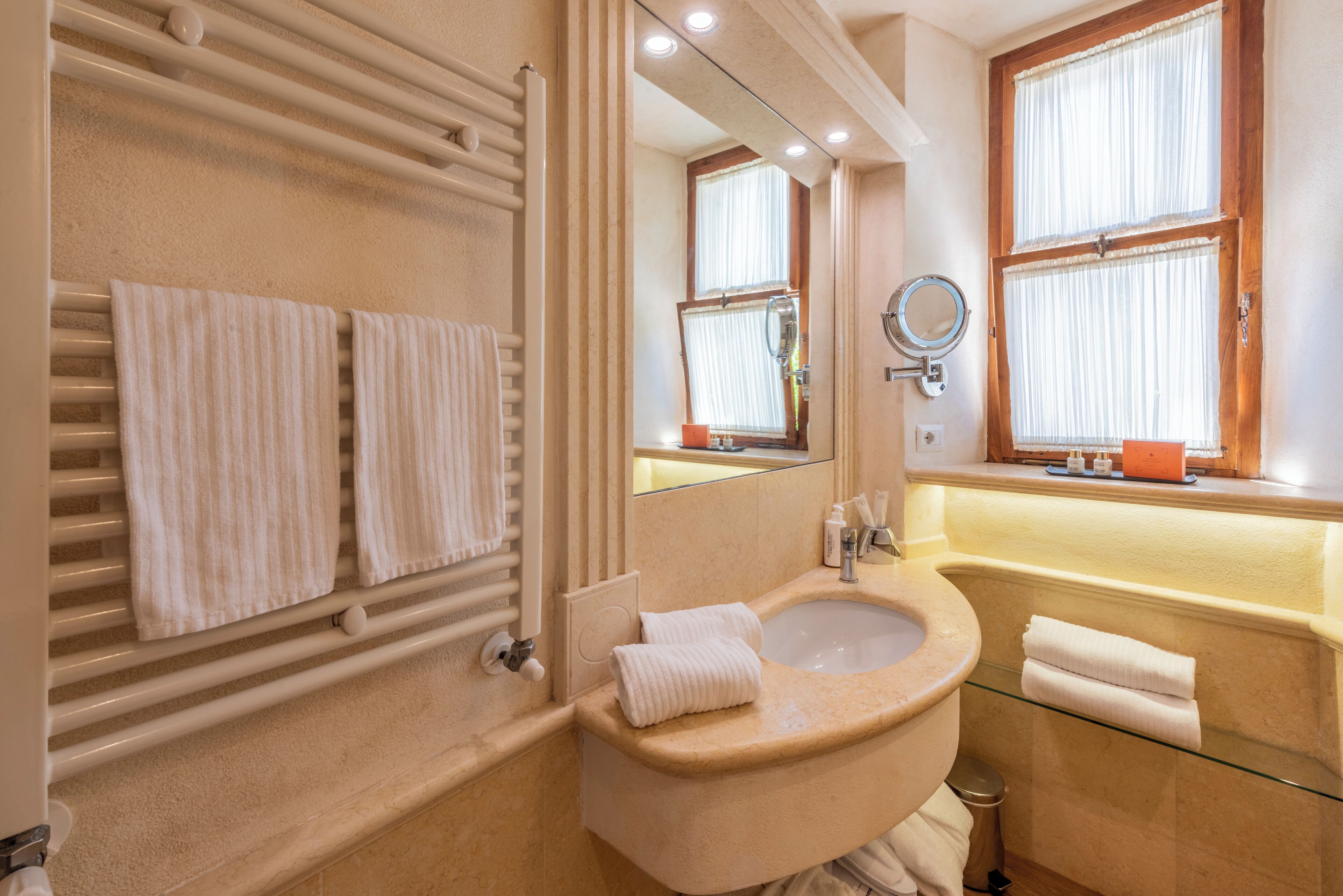 Une salle de bain avec un lavabo beige, un miroir et deux serviettes posées sur un porte-serviettes.