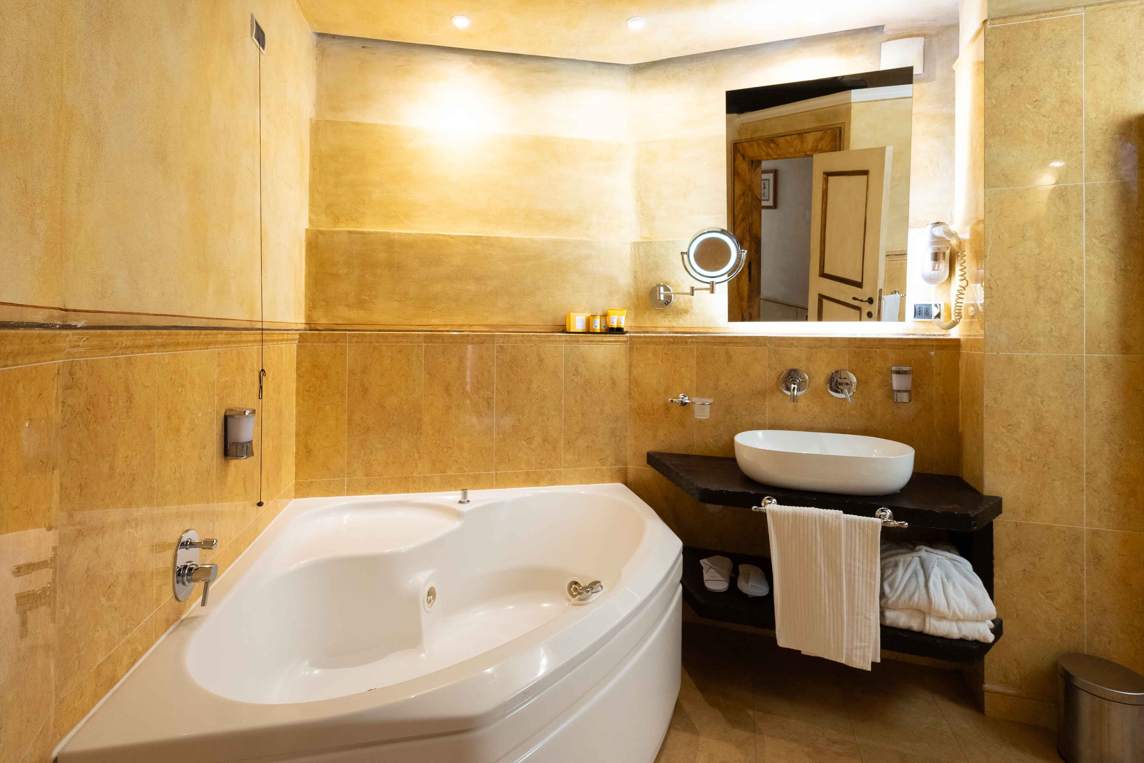 A modern bathroom with a large bathtub, a sink, and a vanity with a towel rack.