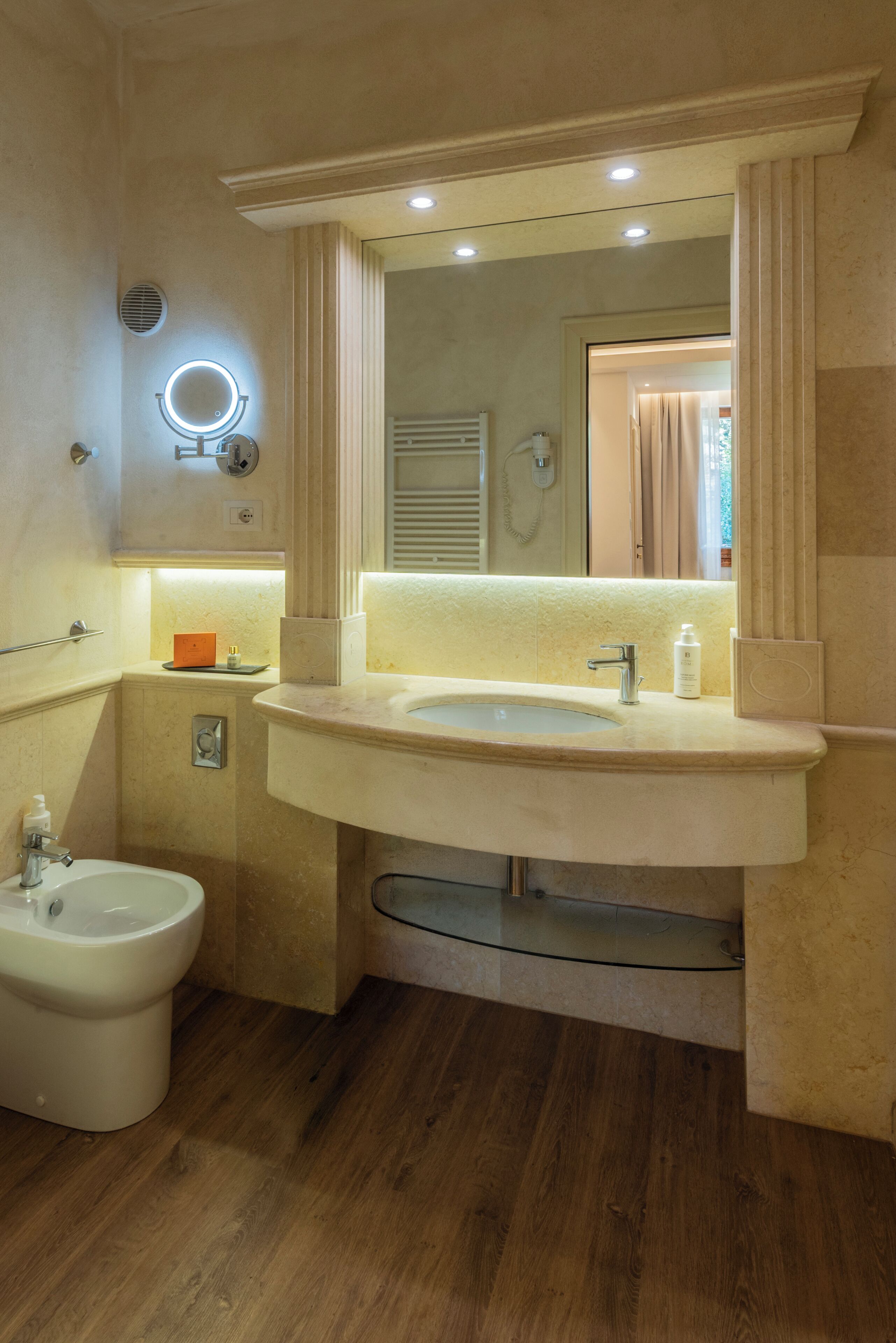 A bathroom with a large sink, a mirror, a bidet, and a glass shower enclosure.