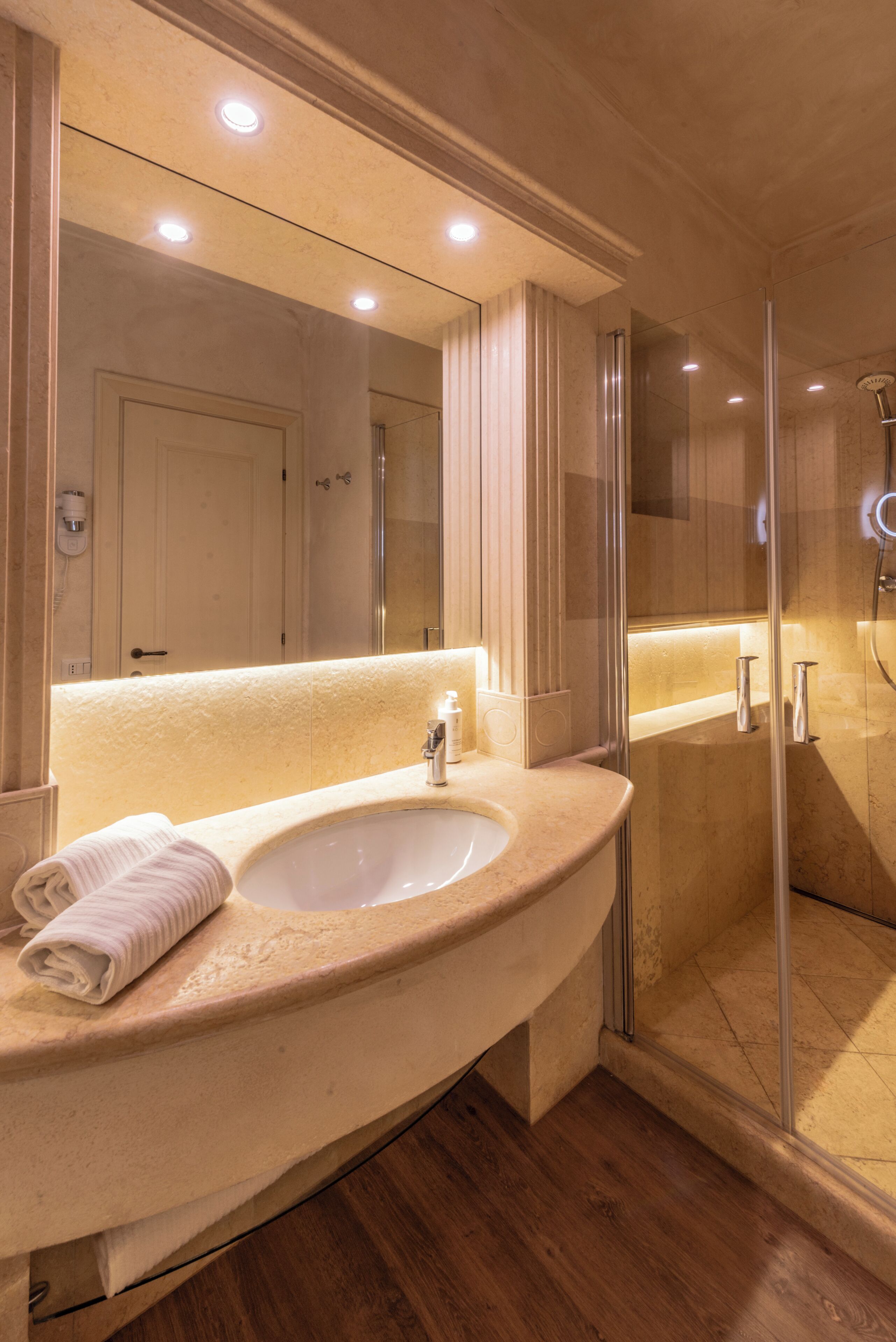 A bathroom with a sink, mirror, and shower.