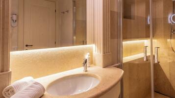 A bathroom with a sink, mirror, and shower.