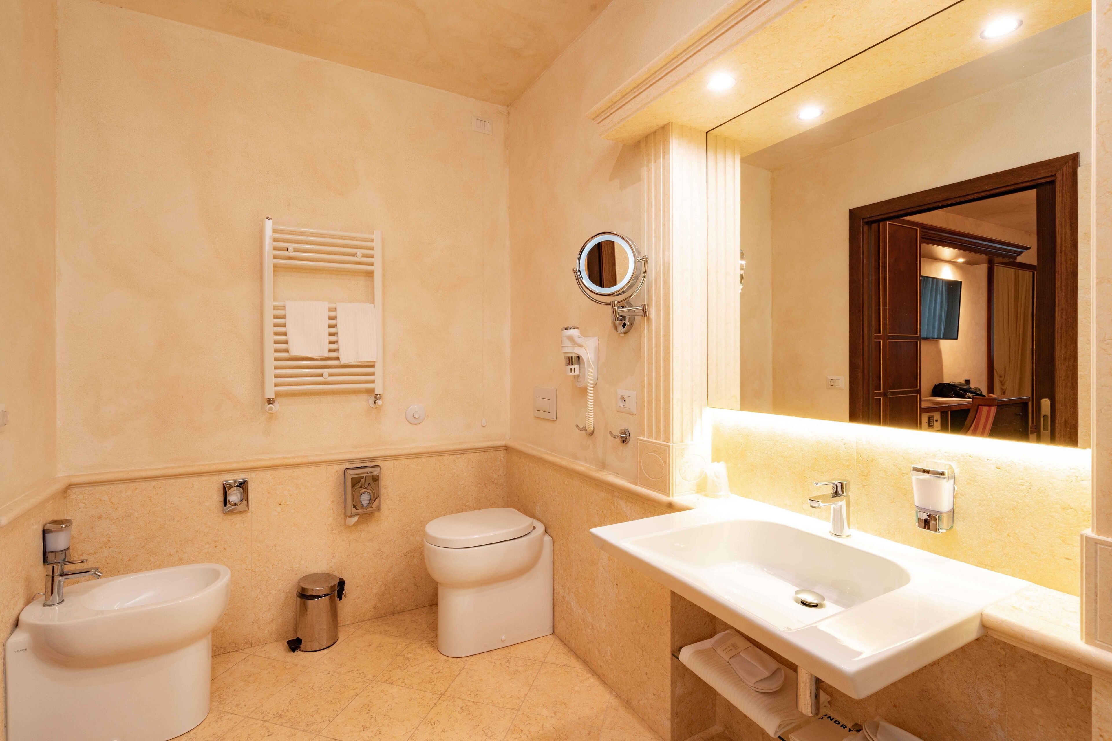 Une salle de bain équipée d’un lavabo, d’un bidet, de toilettes et d’un porte-serviettes.