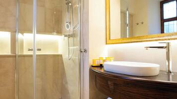 Un baño moderno con cabina de ducha acristalada, un lavabo blanco y un espejo grande.