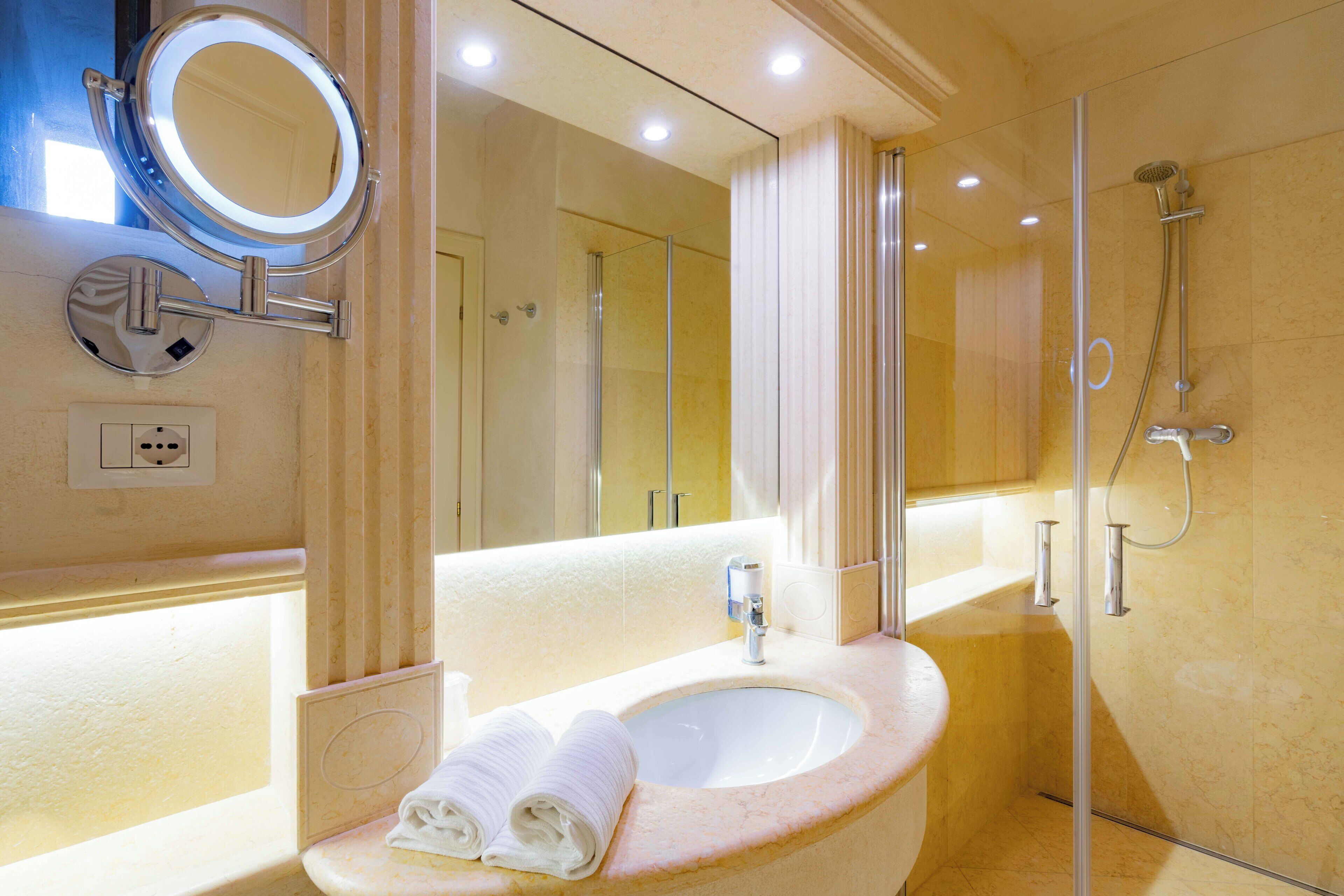 A bathroom with a sink, mirror, and shower.