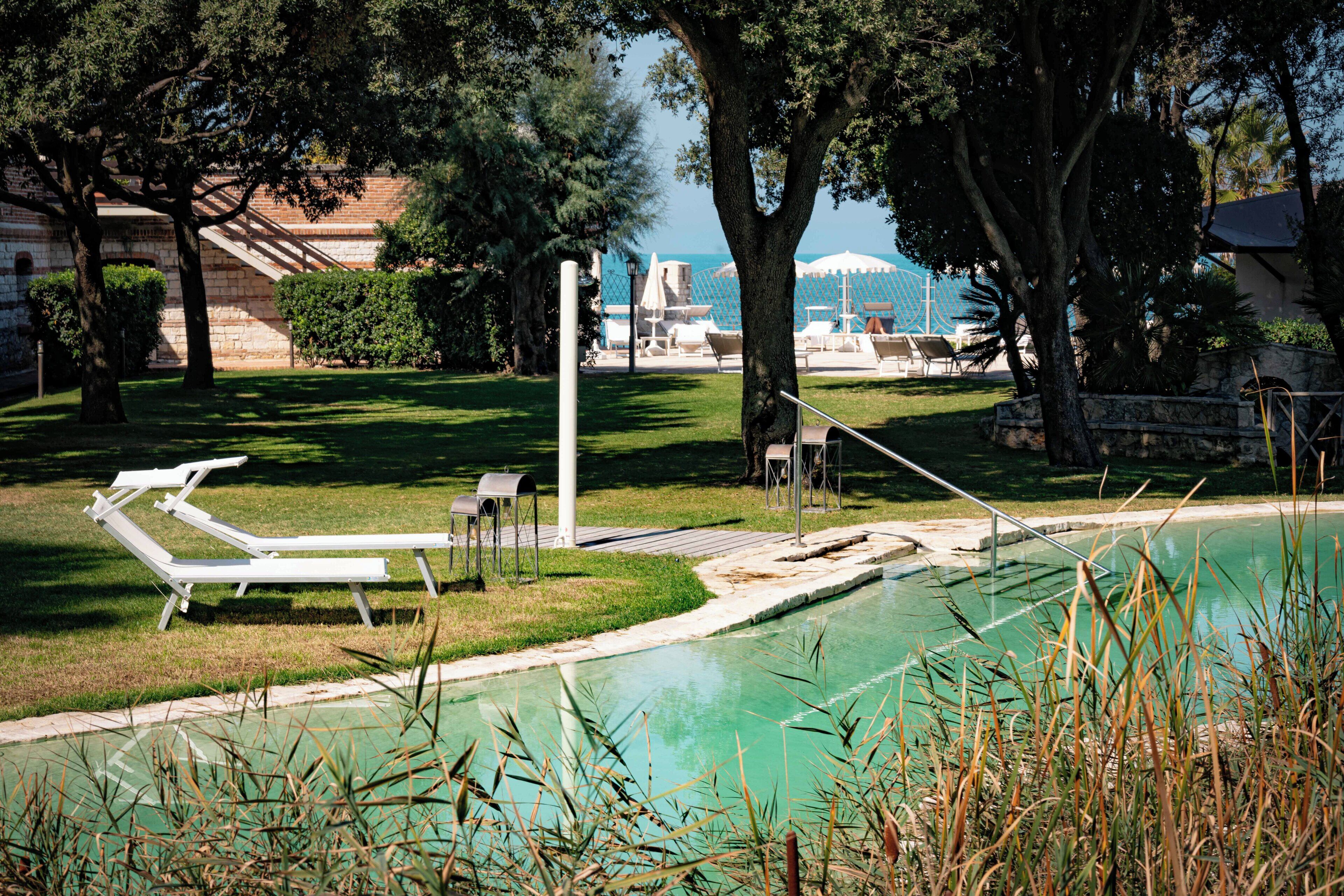Zona de piscina con sillones de descanso, una piscina pequeña y vista al mar.