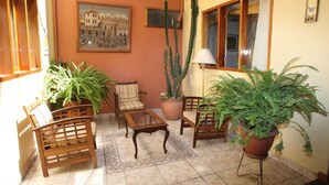 Ein gemütlicher Patio-Bereich mit Holzmöbeln, Topfpflanzen und einer großen Sukkulente.