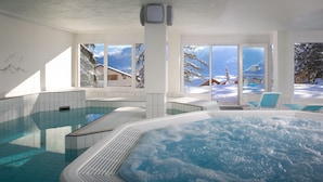 Una piscina interior moderna con vistas despejadas a montañas nevadas a través de amplios ventanales.