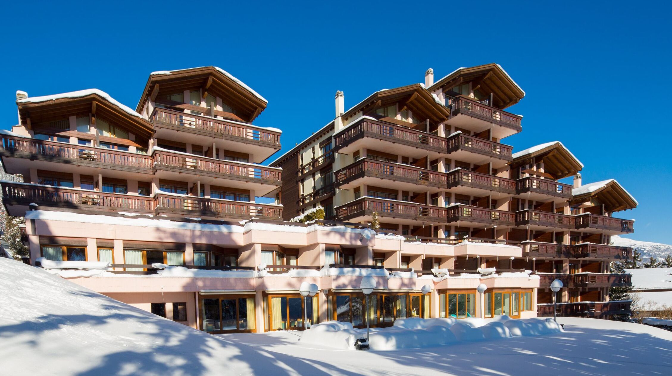 A multi-story hotel with balconies, large windows, and a snowy landscape.