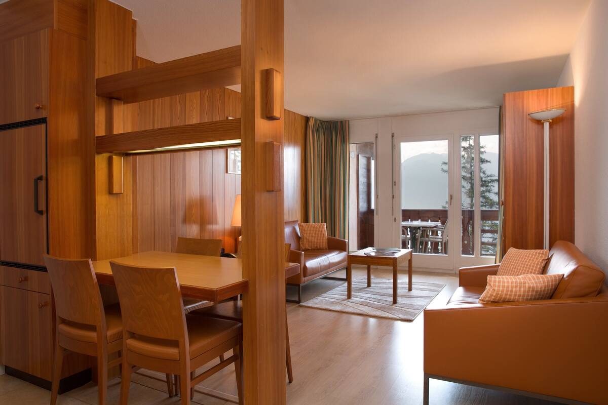 Een moderne woonkamer met houten meubels, een bank en een eettafel.